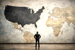 A lone figure facing a large world map where the United States dominates the scene, highlighting a contrast of scale and perspective.