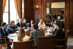 Moderate politicians debating while organized ideological operatives influence institutions in the background