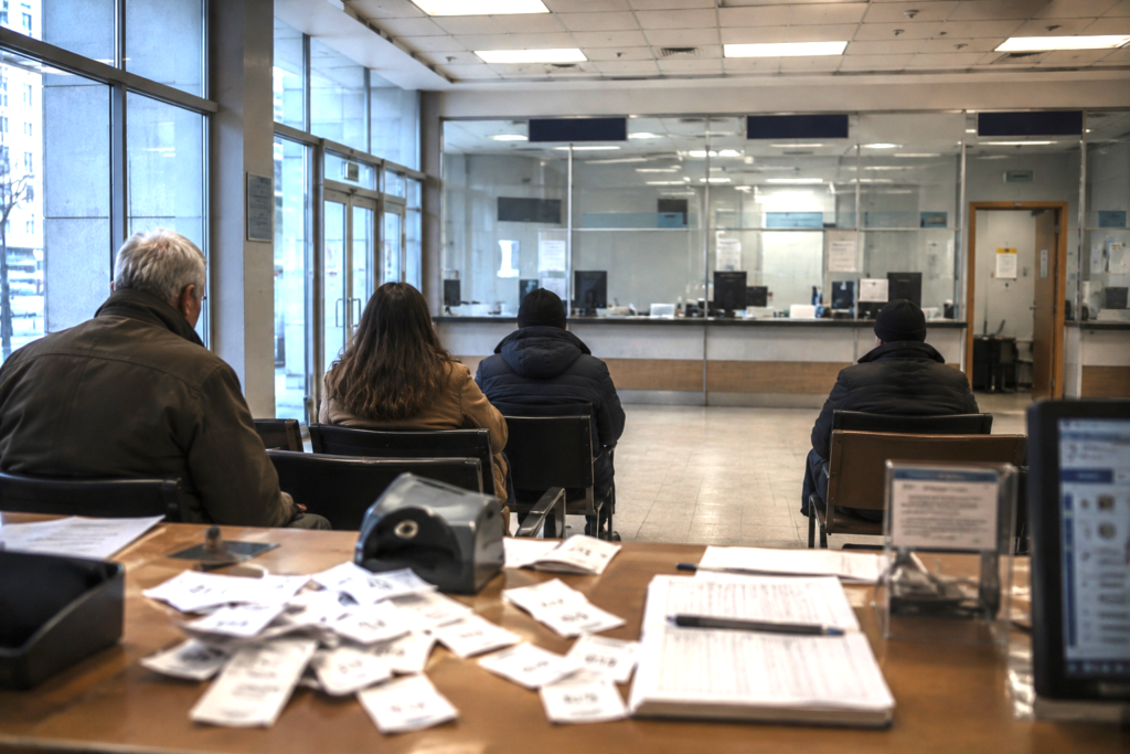 Citizens waiting outside an empty public office with unattended service counters, symbolizing bureaucratic paralysis and loss of real freedom.