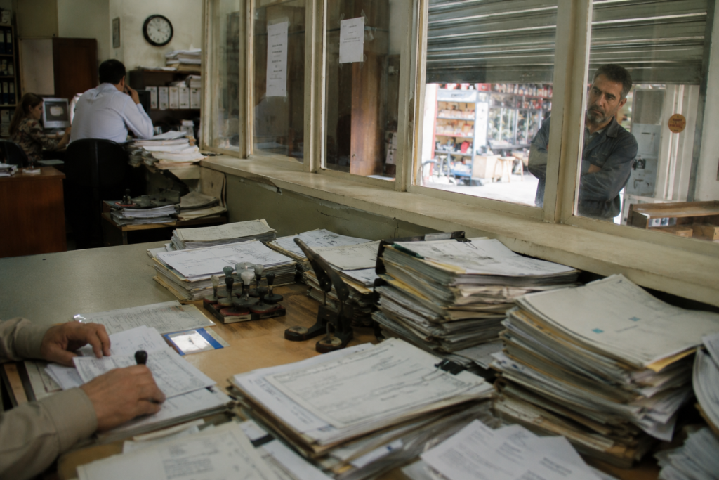 A small business owner facing a bureaucratic office symbolizing overregulation.