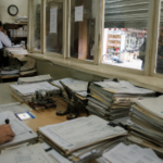A small business owner facing a bureaucratic office symbolizing overregulation.