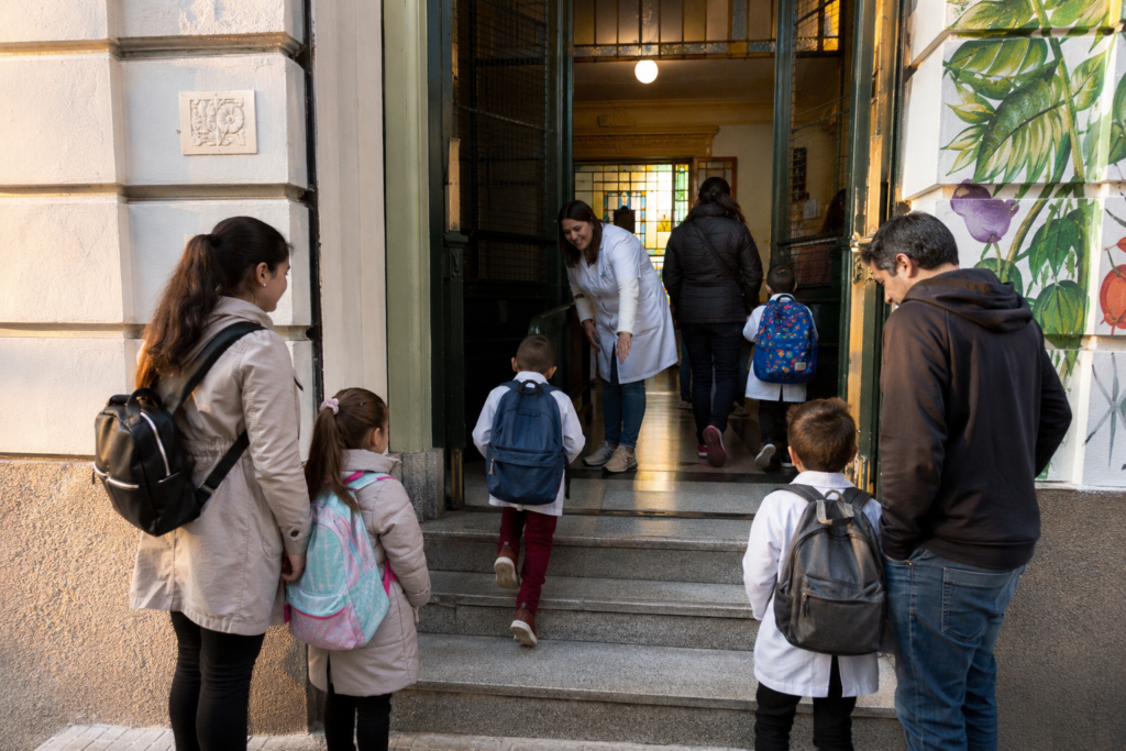 Uruguayan children entering school with families at dawn, symbolizing education, human capital and social mobility.