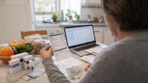 Uruguayan retiree reviewing pension deductions beside household bills and medication.