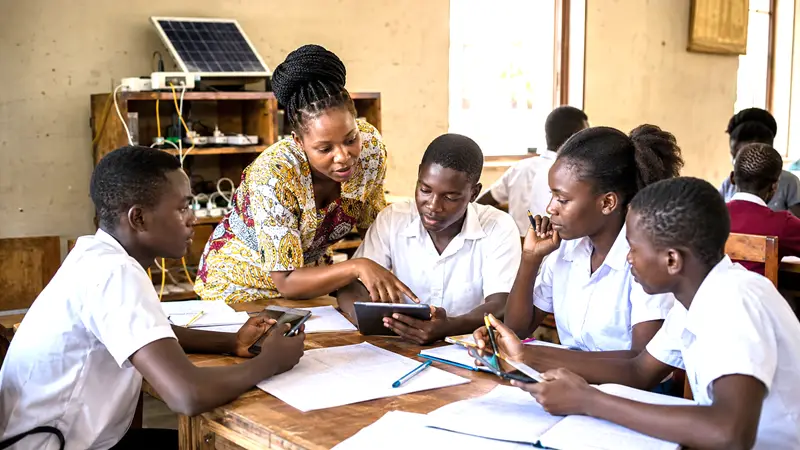 African students using AI-assisted learning tools while a teacher guides a collaborative reasoning exercise.