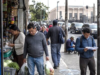 Workers and families in a Latin American city near a government building, illustrating the contrast between public-sector privilege and economic pressure.