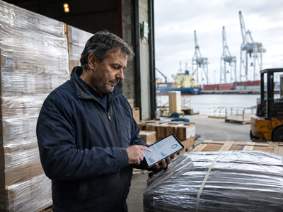Uruguayan logistics worker reviewing finances in a warehouse overlooking Montevideo’s port.