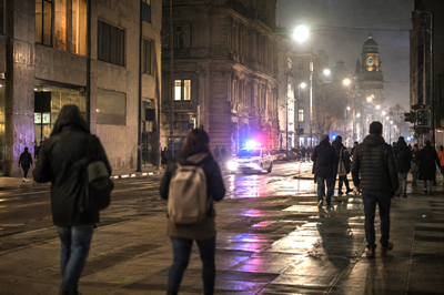 Nighttime street scene in Montevideo with a police patrol and pedestrians, evoking the tension between political history and public security.