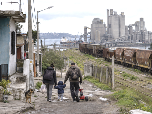 Uruguayan family walking near aging railway and industrial infrastructure.