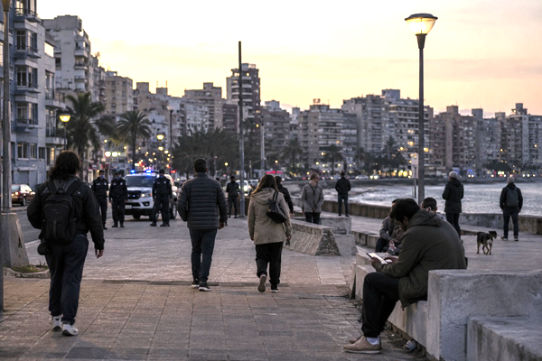 Residents in an urban neighborhood in Uruguay with a police patrol in the background, illustrating the debate over security and democratic limits.