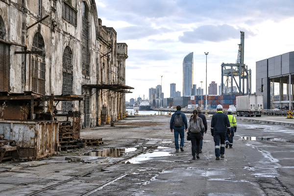 Aging urban and industrial infrastructure in Montevideo contrasted with anonymous workers moving toward a modern economic environment.