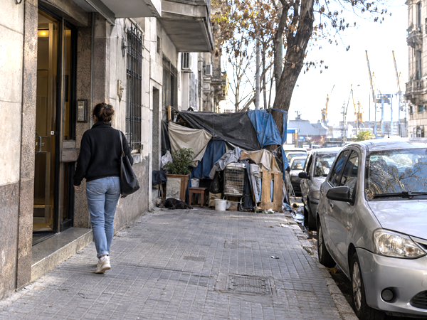 Montevideo resident facing an obstructed sidewalk and parked car in an everyday urban scene.